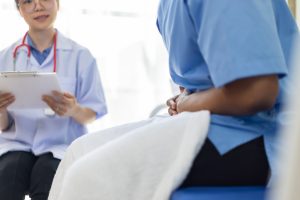 doctor consulting someone holding stomach in pain